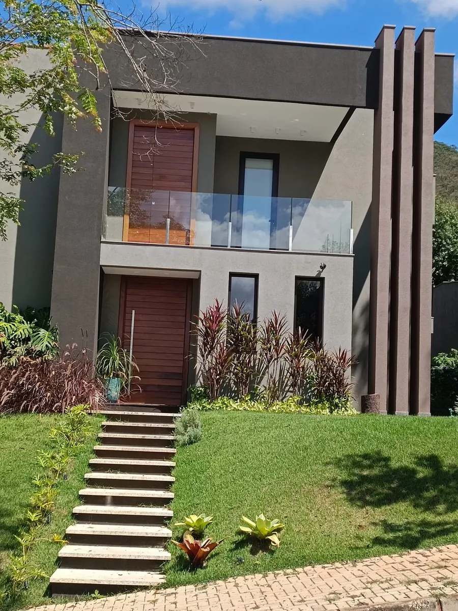Fachada de casa contemporânea com jardim frontal plantado e gramado